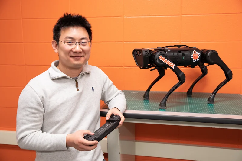 Professor poses with quadruped robotic dog.