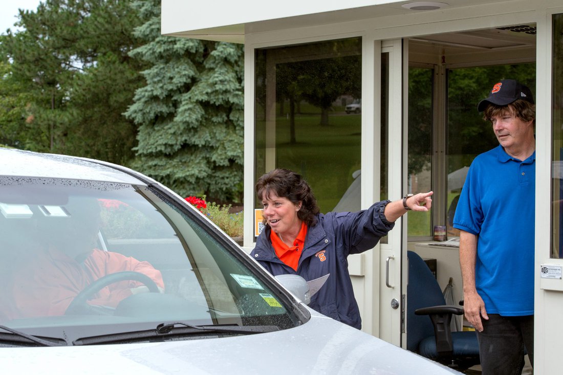 Parking booth attendants direct a car through campus