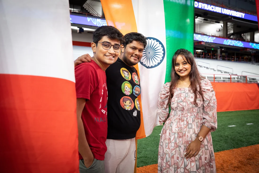 Students pose together at international Thanksgiving dinner surrounded by international flags.