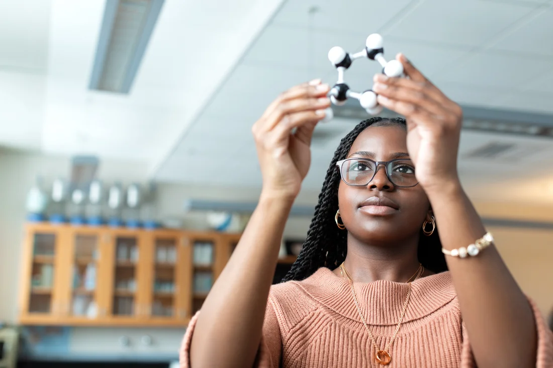 Class of 2022, Nathena Murray examines a model of an atom.