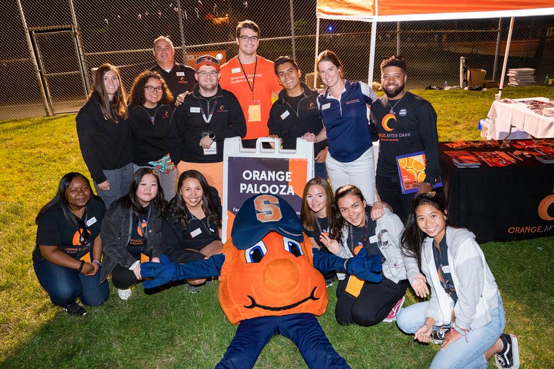Students pose for photo at orange after dark event