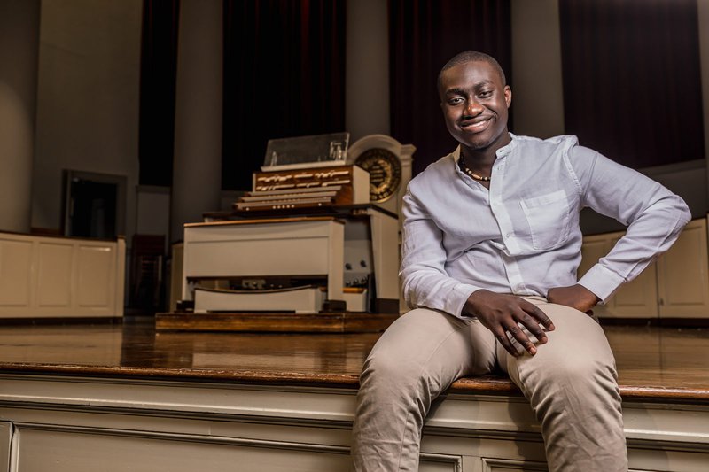 Portrait of Samuel Kuffuor Afriyie sitting on Hendrick's Chapel Stage. Click the image to read his story.