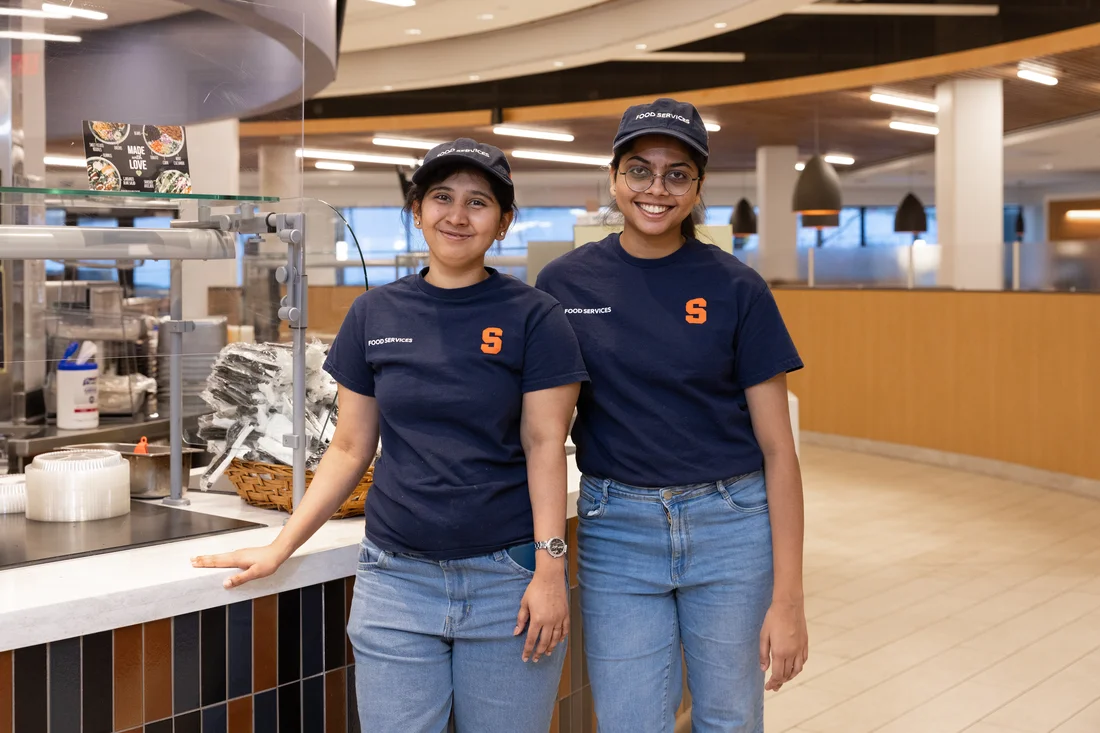 Two food service staff members standing and smiling together.