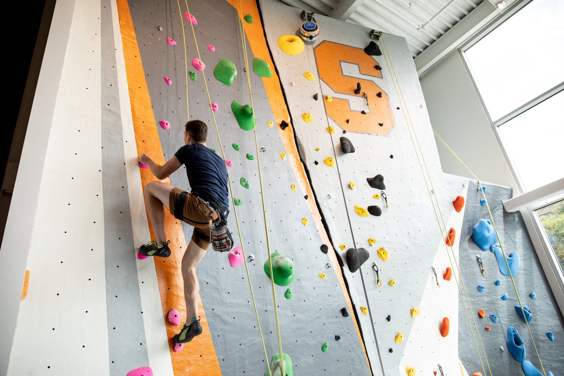 Student climbs the rock wall at the Barnes Center at The Arch