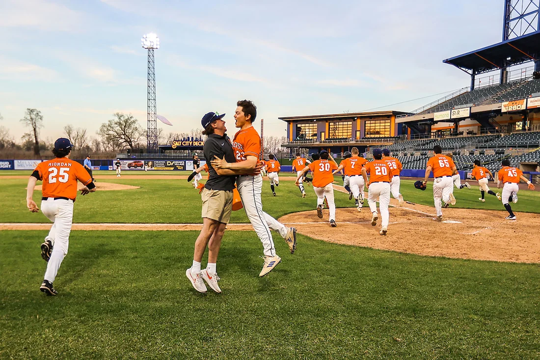 Two people chest bumping on a baseball field.