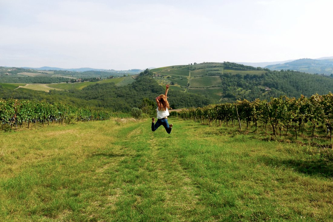 Student jumping in the air while visiting a vineyard in Italy